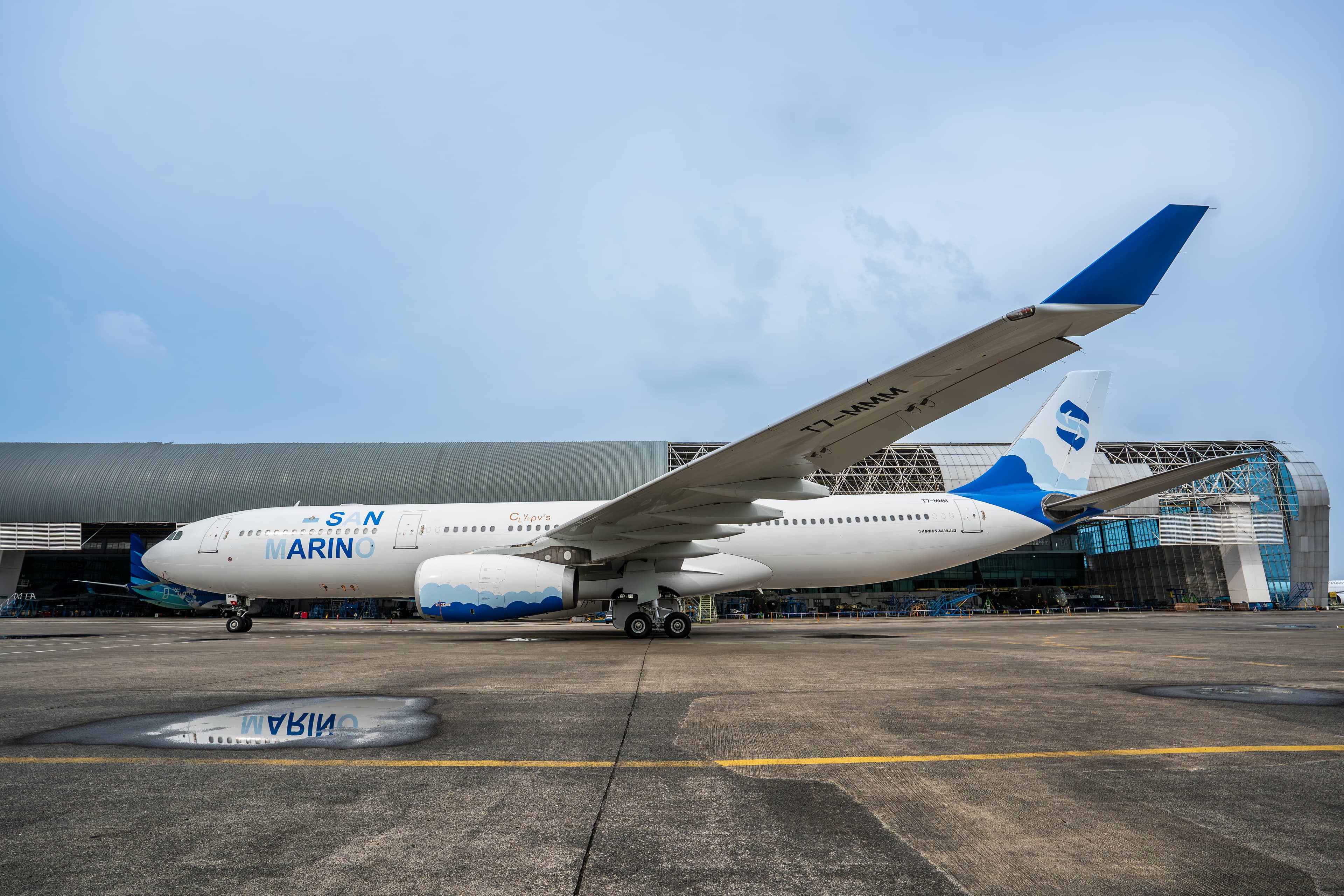 Airbus A330-300 T7-MMM in San Marino livery on the apron in front of a maintenance hangar
